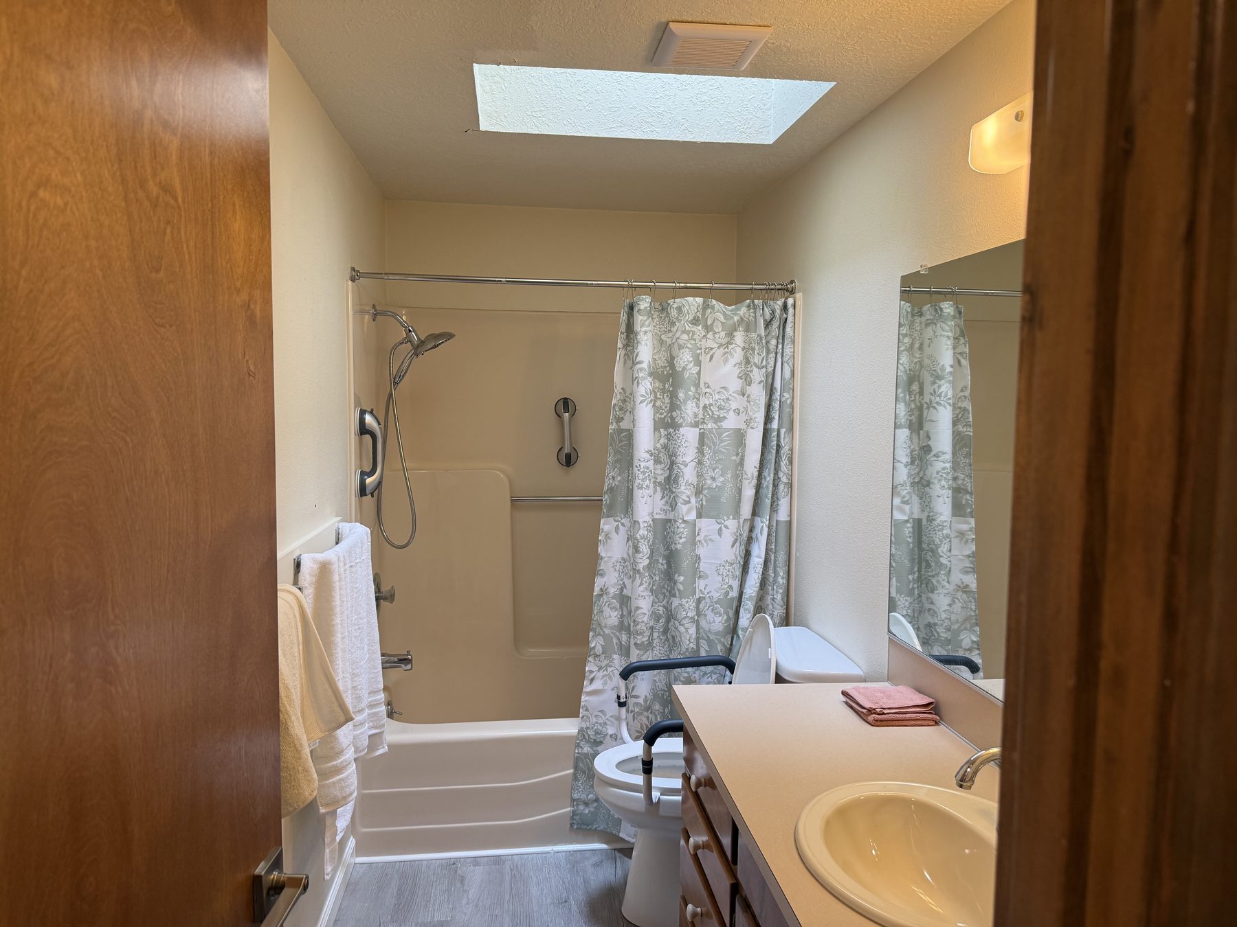 Bathroom with tub, grab bars, and skylight